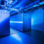 Blue-lit data centre room featuring the VEGA supercomputer and Atos BullSequana cabinets.