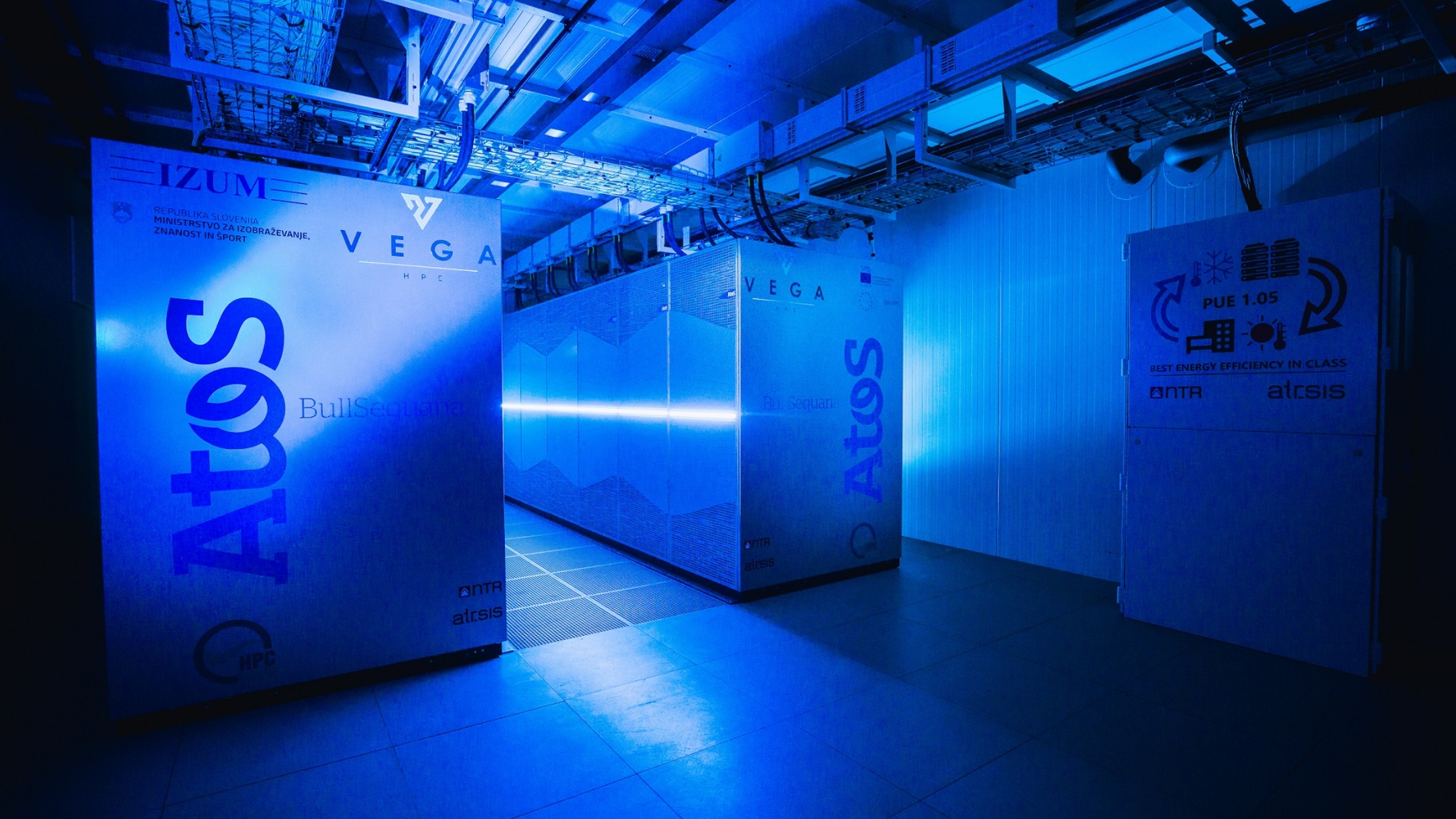 Blue-lit data centre room featuring the VEGA supercomputer and Atos BullSequana cabinets.