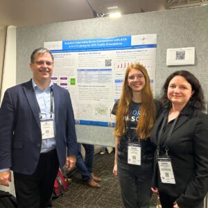Three presenters standing in front of an HPC poster on scalable route computation at a conference.