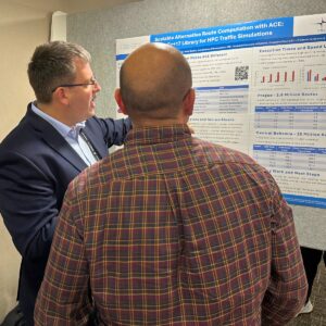 A presenter explaining an HPC research poster to an attendee during a conference session.