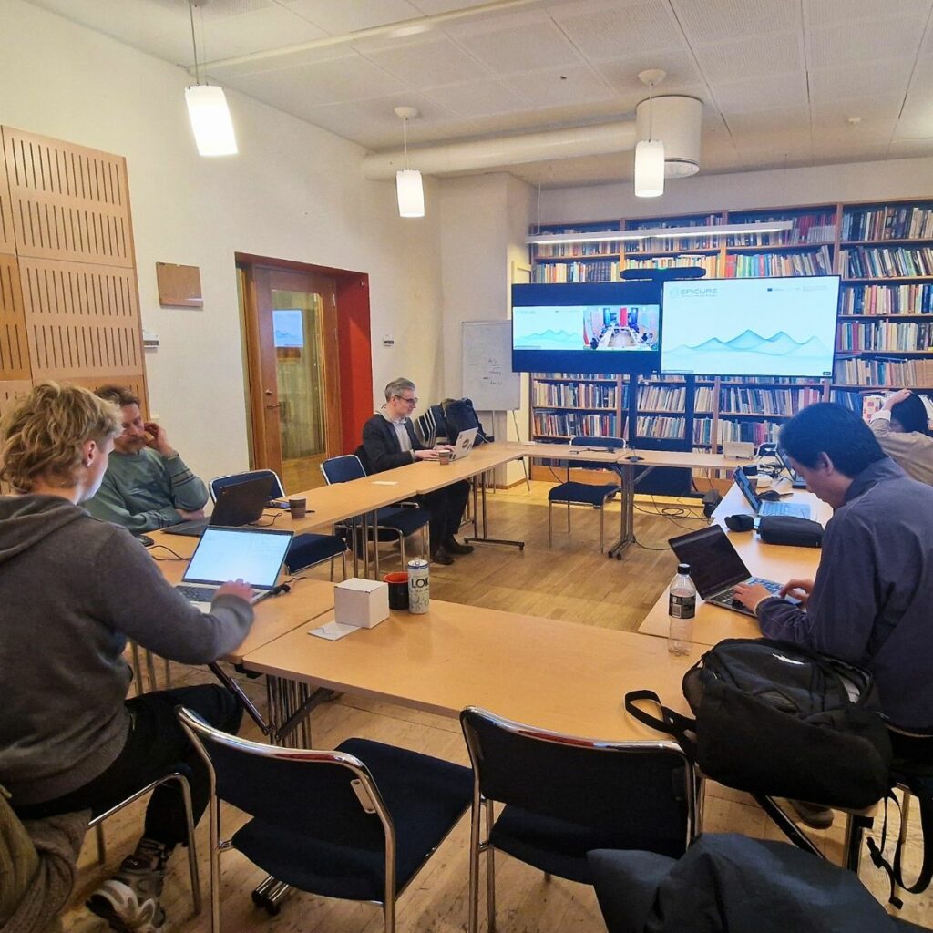 Four people sitting on a U-type desk working at the laptop.