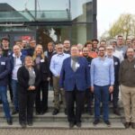 Group of people standing in front of a building entrance, posing for a photo.
