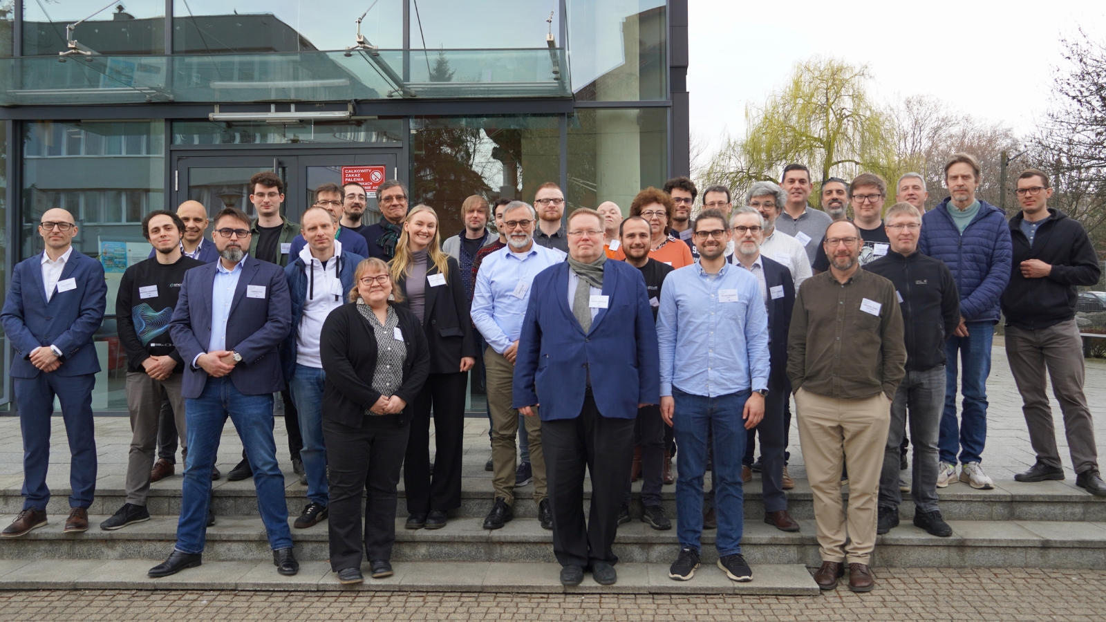 Group of people standing in front of a building entrance, posing for a photo.