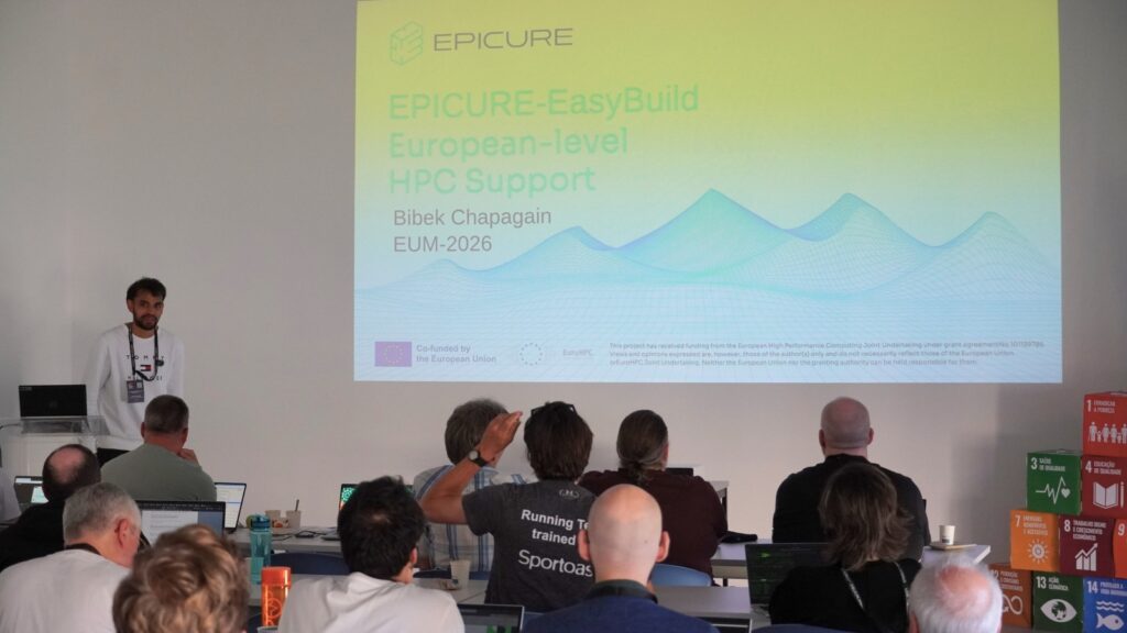Speaker presenting EPICURE–EasyBuild European-level HPC support session to an audience seated with laptops during a workshop.