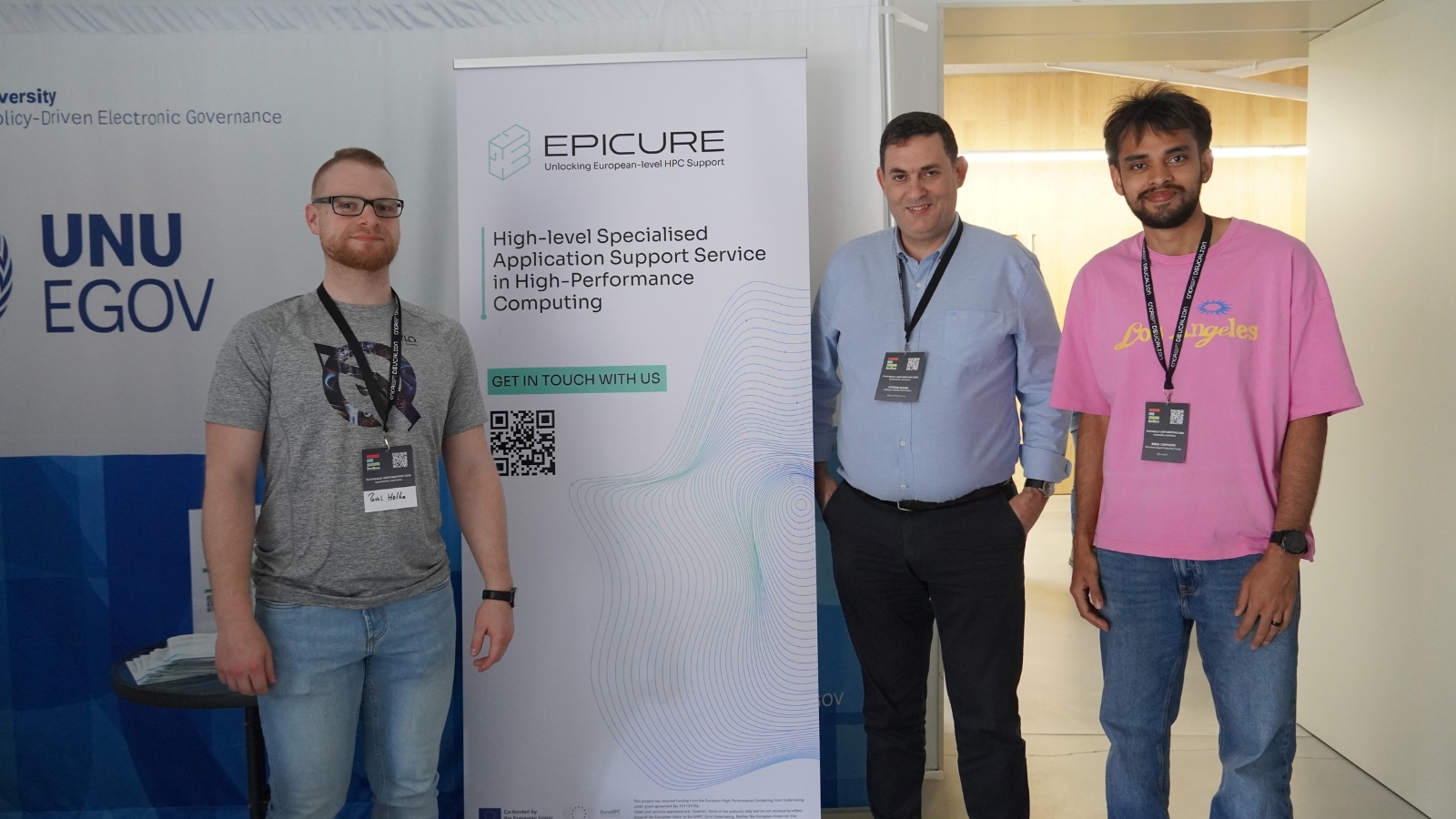 Three participants standing beside an EPICURE banner promoting high-level HPC application support, at a conference booth area.