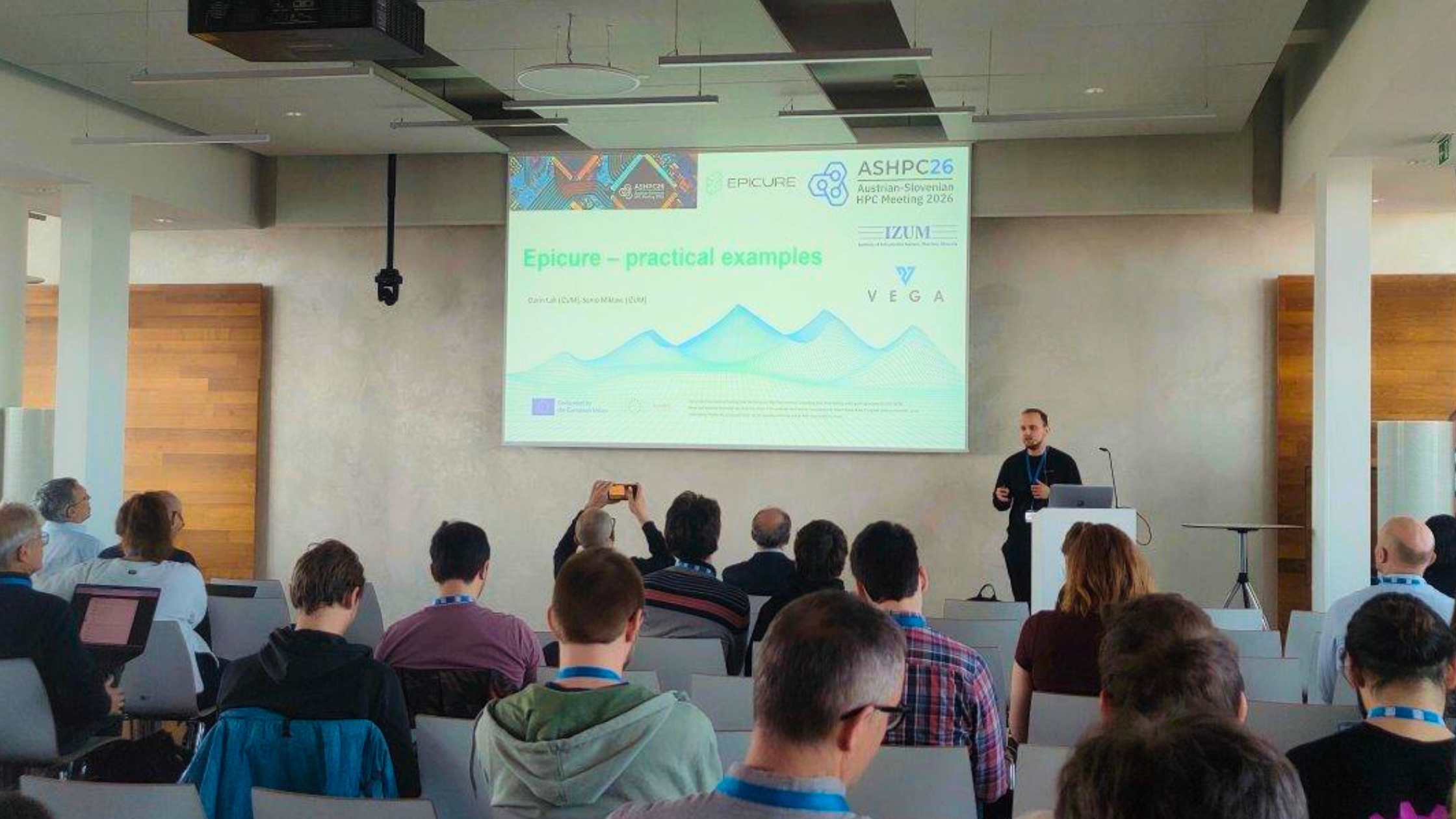 A man delivers a presentation on practical examples of high-performance computing support services to attendees at the Austrian-Slovenian HPC Meeting 2026.