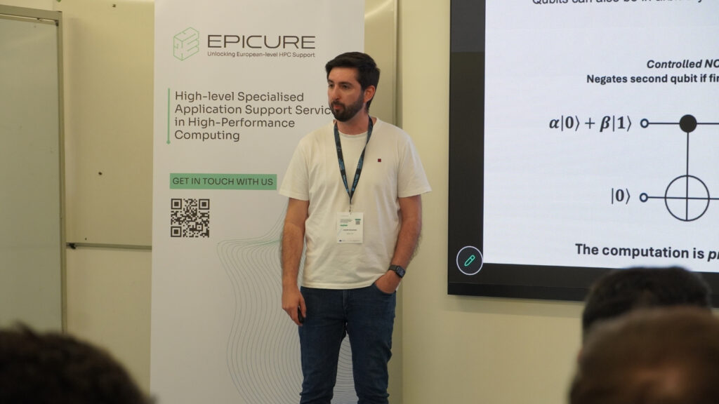 Speaker standing beside an EPICURE banner and presentation screen, explaining a technical concept during an HPC workshop session.