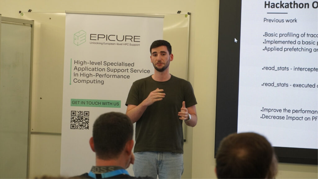 Speaker presenting during an HPC workshop, gesturing while explaining, with an EPICURE banner and a slide outlining hackathon work in the background.