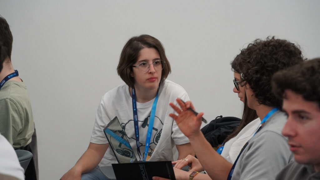 Small group of participants discussing during a workshop, with one person holding a laptop while others engage in conversation.
