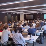 Participants in a modern training room, following a technical presentation on large-scale HPC code optimisation and performance analysis while working on laptops during the hands-on session.