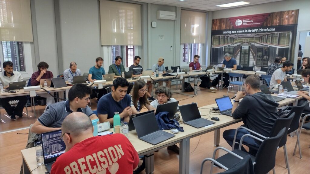 Researchers and developers participate in a workshop, working on laptops and discussing parallel computing tasks in a classroom.
