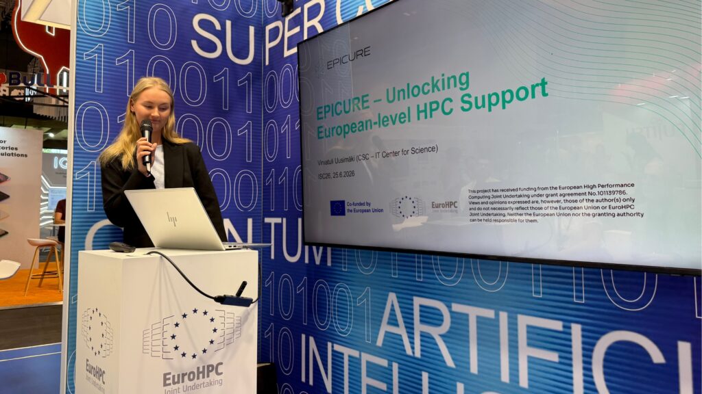 Woman speaking at the microphone presenting the EPICURE project at the EuroHPC Joint Undertaking booth during ISC High Performance 2026 in Hamburg.