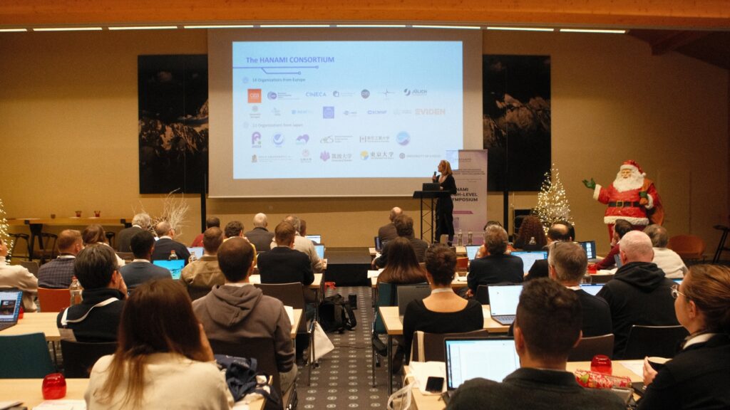 Participants attend a presentation during the HANAMI High-Level Symposium, where a speaker share updates on the EU–Japan collaboration in HPC.